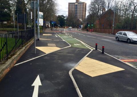 A segregated cycle lane on Wilmslow Road crossing the mouth of a side road